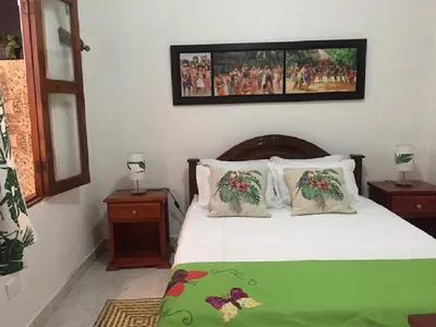 a bedroom with a bed with a green blanket and pillows at Etnias Hotel tematico in Quibdó