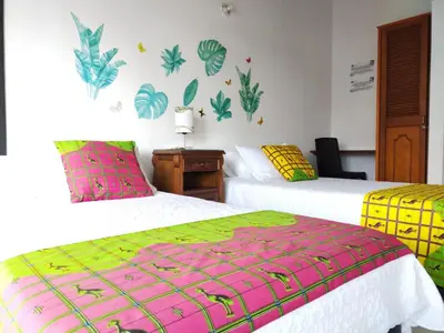 a bedroom with two beds with green and pink at Etnias Hotel tematico in Quibdó