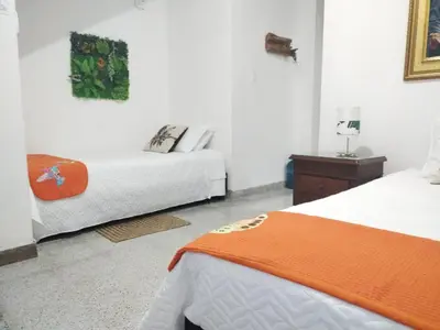 a white room with two beds and a night stand at Etnias Hotel tematico in Quibdó