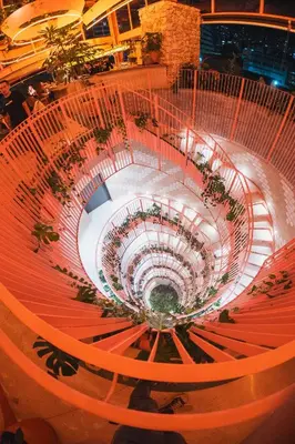 a large spiral staircase in a building with plants at The Somos Bold Hotel in Medellín