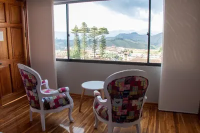 two chairs and a table in a room with a window at Hotel Entre Brumas in Aguadas