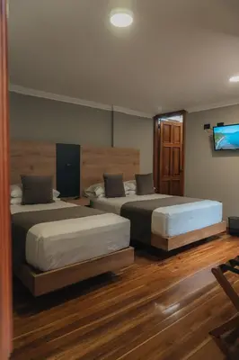 a bedroom with two beds and a flat screen tv at Hotel Entre Brumas in Aguadas