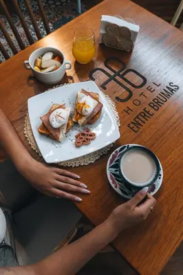 a person sitting at a table with a plate of food at Hotel Entre Brumas in Aguadas