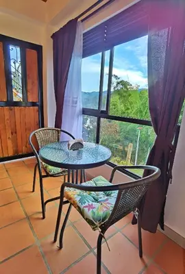 a table and chairs in a room with a window at Descanso Bajo La Piedra Del Peñol in Guatapé