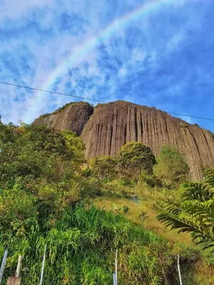 a rainbow in the sky over a large mountain at Descanso Bajo La Piedra Del Peñol in Guatapé