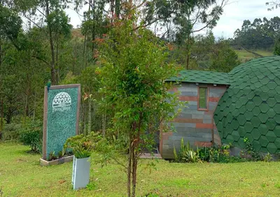 a small house with a green roof next to a tree at PrivaDome in Rionegro