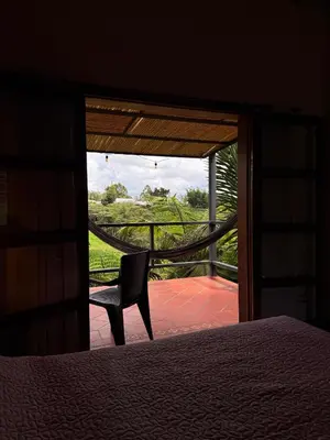a bedroom with a bed and a chair in front of a door at San José de las bromelias in Marinilla