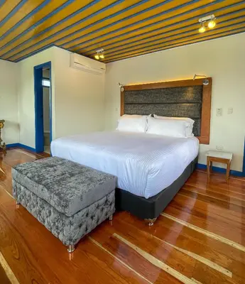 a bedroom with a large bed and a ottoman at Atardeceres del Cafe in Manizales