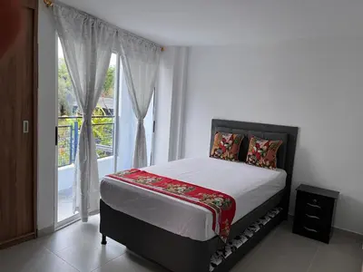 a bedroom with a bed and a large window at Travelu Guatape Apartamento in Guatapé