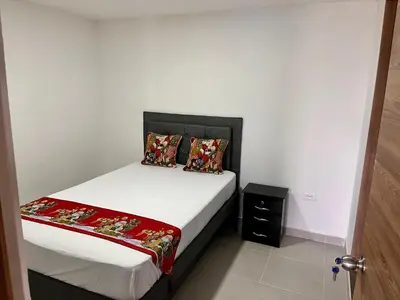 a small bedroom with a bed with white sheets and pillows at Travelu Guatape Apartamento in Guatapé