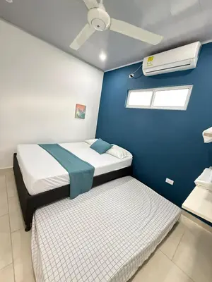 a bedroom with two beds and a blue wall at TORRES DEL MESÓN LUXURY APARTA HOTEL Doradal in Doradal