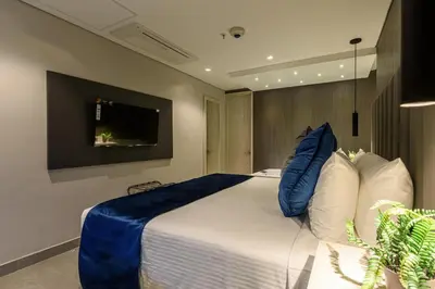 a bedroom with a large bed and a tv on the wall at 4 Sur Hotel in Medellín