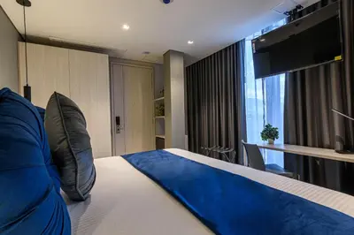 a hotel room with a bed with a blue blanket at 4 Sur Hotel in Medellín