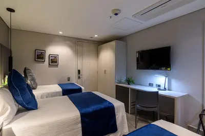a hotel room with two beds and a desk at 4 Sur Hotel in Medellín