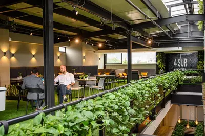 a group of people sitting at tables in an office with plants at 4 Sur Hotel in Medellín