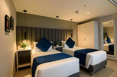 a hotel room with two beds with blue pillows at 4 Sur Hotel in Medellín