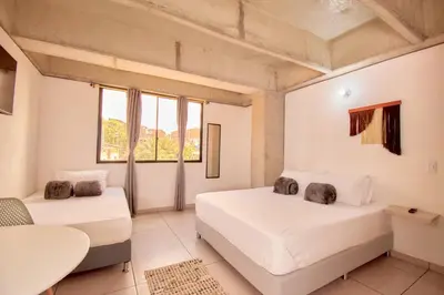 a bedroom with two beds and a table and windows at Mangata Living by Bernalo Hotels in Medellín