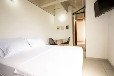 a bedroom with a white bed and a table and chairs at Mangata Living by Bernalo Hotels in Medellín