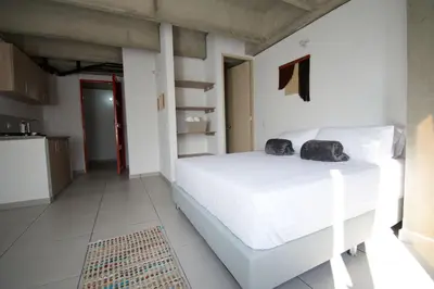 a bedroom with a white bed with two black bags on it at Mangata Living by Bernalo Hotels in Medellín
