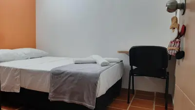 a bedroom with a bed and a black chair at PRIMAVERA LIVING in Medellín