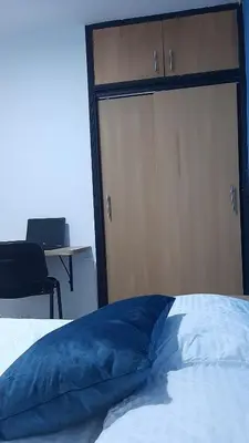 a bed with a blue pillow in front of a closet at PRIMAVERA LIVING in Medellín