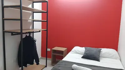 a room with a bed and a red wall at PRIMAVERA LIVING in Medellín