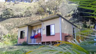 a pink and white house on the side of a hill at Cabaña La Guitarra in Betania