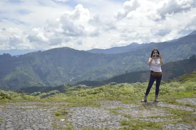 a woman taking a picture of a mountain at Cabaña La Guitarra in Betania