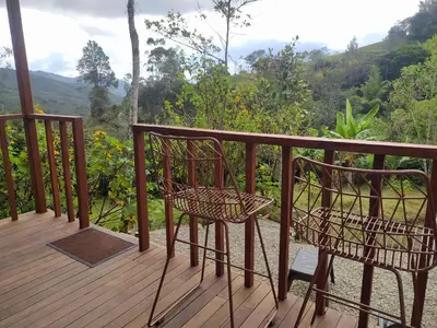 a balcony with a chair and a view of the mountains at Cabaña Momotus I in Concepción