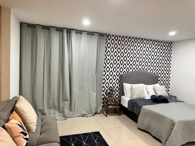 a bedroom with a bed and a couch and curtains at 1208 Beautiful apartment, exclusive area in the poblado in Medellín