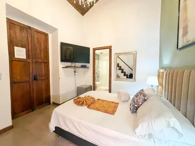a bedroom with a white bed and a wooden door at Hotel Recuerdos de mi Tierra El Poblado Provenza in Medellín