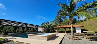 a swimming pool with a palm tree and a pavilion at La escondida in Guarne