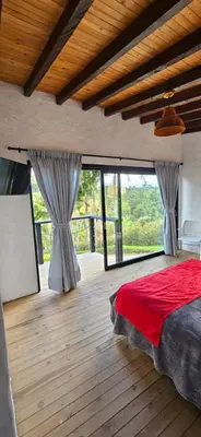 a bedroom with a red bed and large windows at La escondida in Guarne