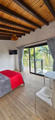 a bedroom with a bed and a table and some windows at La escondida in Guarne