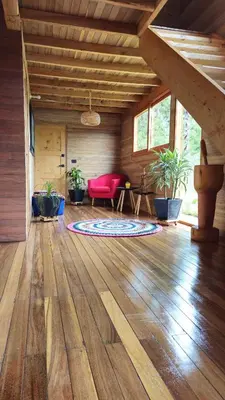 a living room with a red couch and a wooden floor at Beehouse Arví Cabaña in Guarne