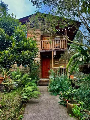 a house with a wooden porch and a balcony at Beehouse Arví Cabaña in Guarne