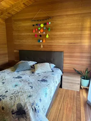 a bedroom with a bed and a wooden wall at Beehouse Arví Cabaña in Guarne