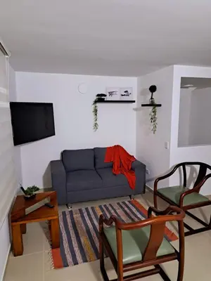 a living room with a blue couch and a tv at Aparta Hotel Jardines de Guatape By Hope in Guatapé
