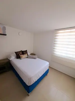 a bed in a white room with a window at Aparta Hotel Jardines de Guatape By Hope in Guatapé