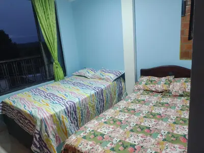 two beds in a room with a window at ApartaHotel El Balcón del Tolima in Falan