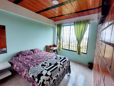 a bedroom with a bed and a large window at ApartaHotel El Balcón del Tolima in Falan