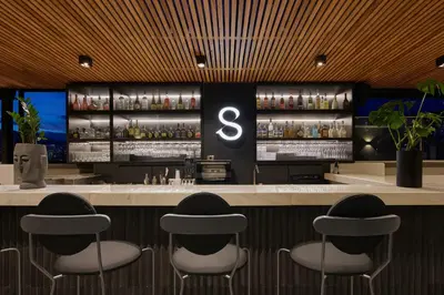 a bar with four stools at a bar with a number six at Hotel Selis in Medellín