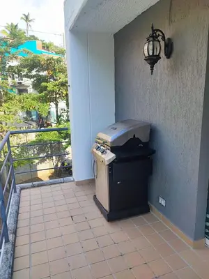 an outdoor grill on a patio with a balcony at Apartasol privado Santa Fe de Antioquia in Santa Fe de Antioquia