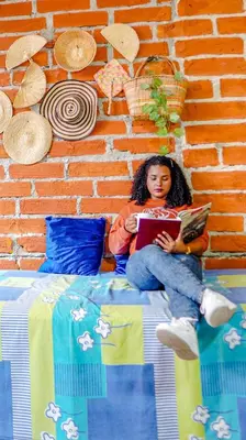 a woman sitting on a bed reading a book at Spring Hostel in Medellín
