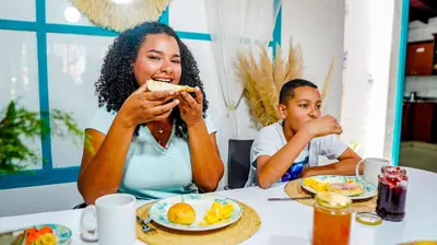 a woman and child sitting at a table eating food at Spring Hostel in Medellín