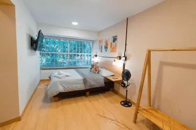 a bedroom with a bed and a desk and a window at Arrendamiento nuevo apartamento con balcón By Roots Rentals NID202 in Medellín