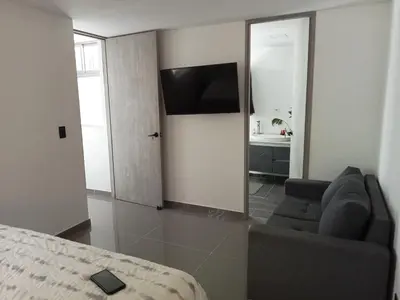 a bedroom with a couch and a television in a room at nuevo amanecer in Bello
