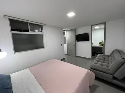 a bedroom with a bed and a chair and a television at nuevo amanecer in Bello