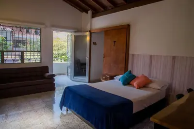 a bedroom with a bed and a couch and a window at CASA DE LOLA in Medellín