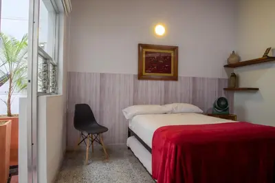 a bedroom with a bed and a chair and a window at CASA DE LOLA in Medellín